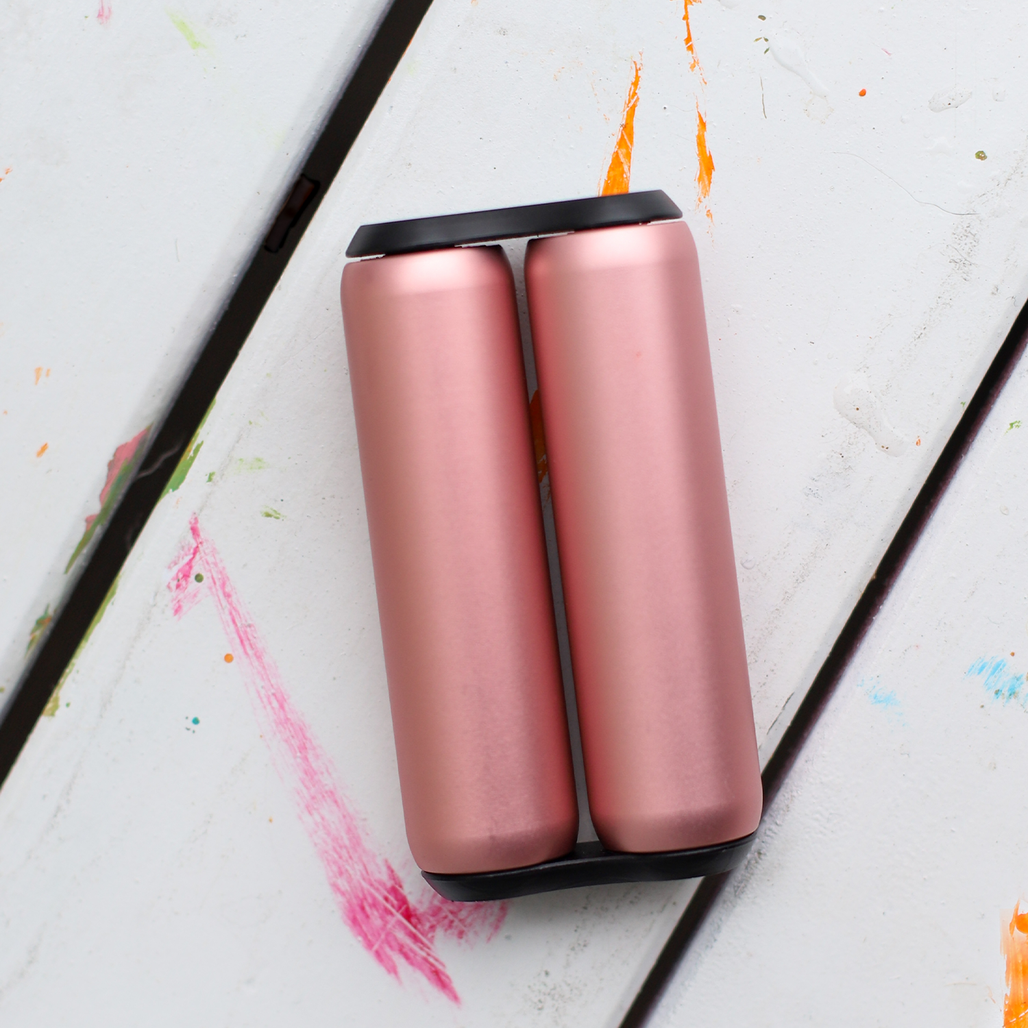 eam_rose_full | Rose gold ONO silent fidget roller on white surface with colorful paint marks