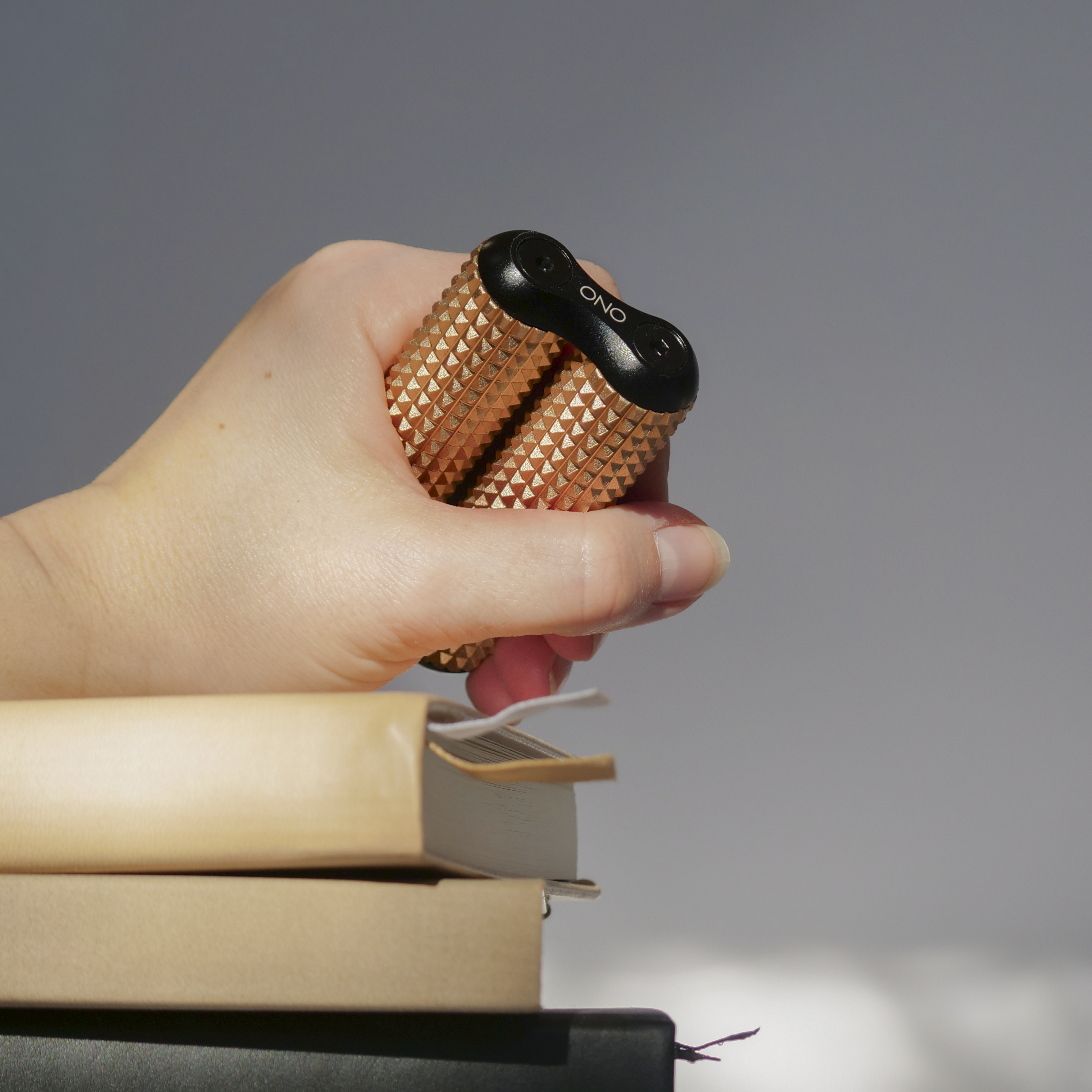 eam_Dune Acupressure_all | Hand holding Dune ONO Roller Acupressure above books