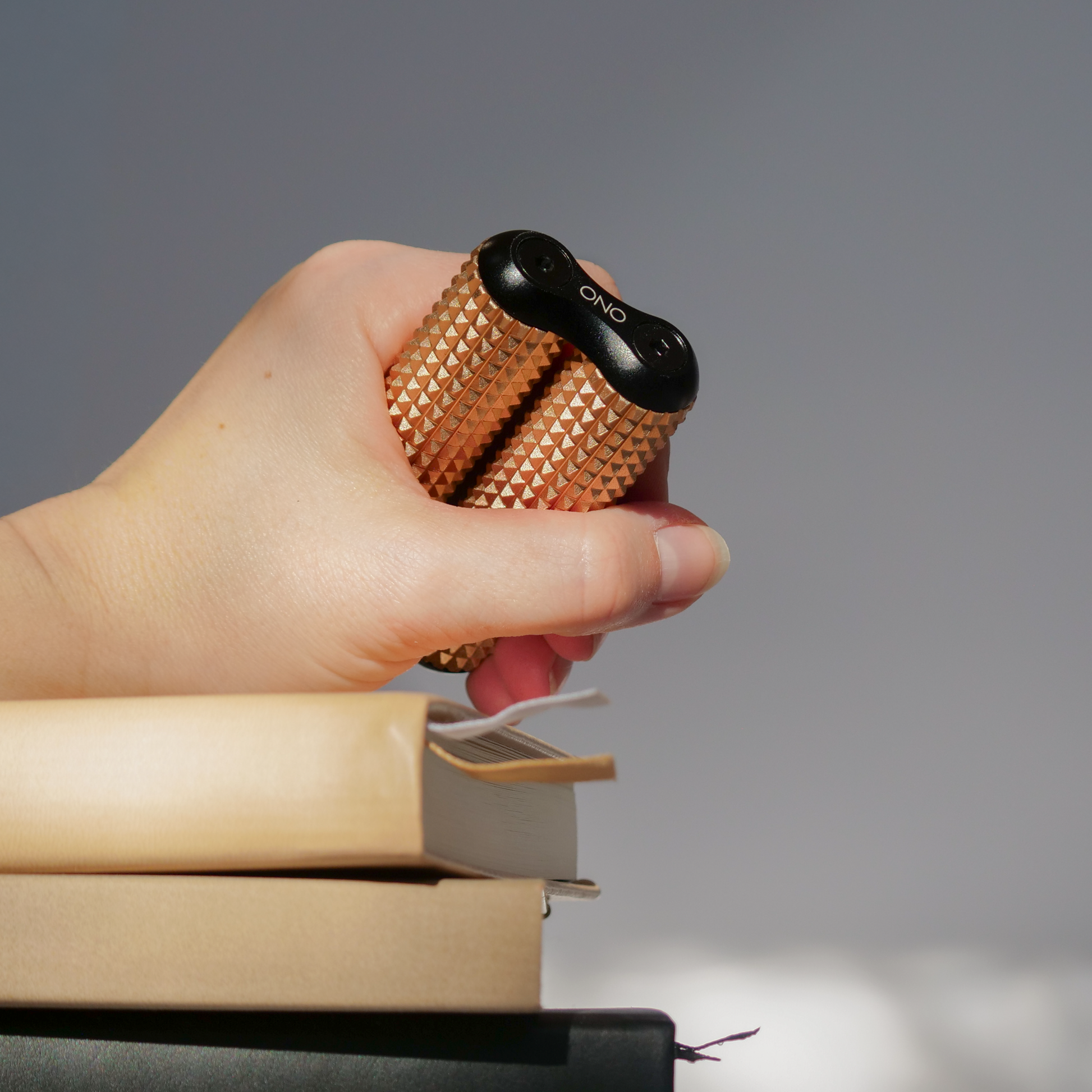 eam_Dune Acupressure_all | Hand holding Dune ONO Roller Acupressure above books